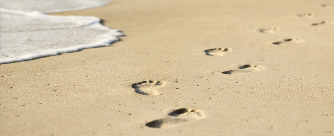 Scenic sandy coastline with footprints and waves.